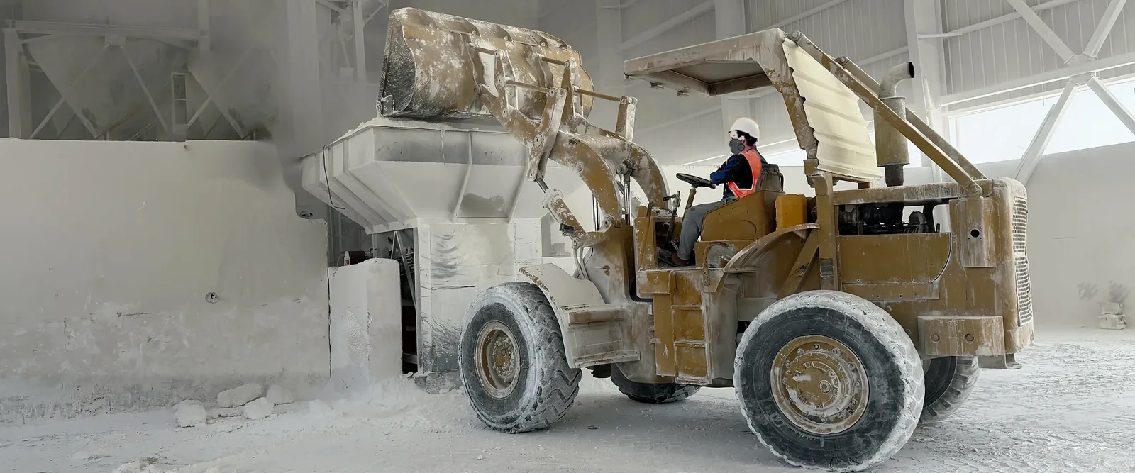 Wheel loader coated in calcium carbonate dust working beside the feed hopper at our plant